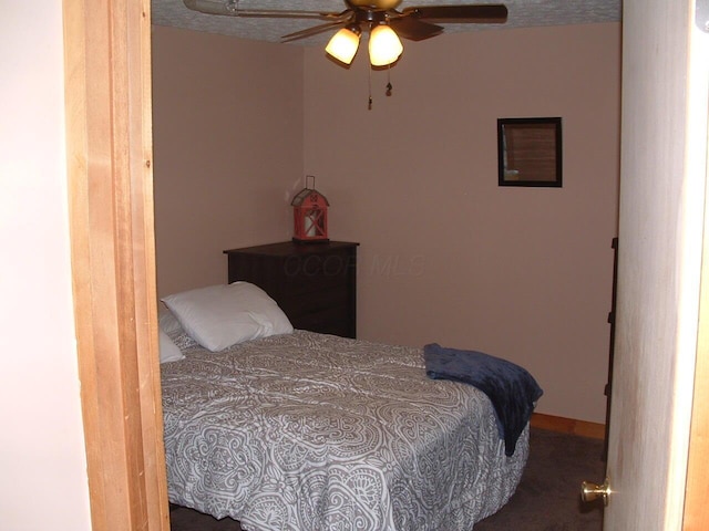 bedroom featuring a textured ceiling, dark carpet, and ceiling fan