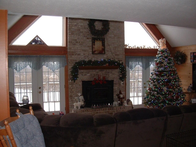 living room featuring french doors, lofted ceiling, and a brick fireplace