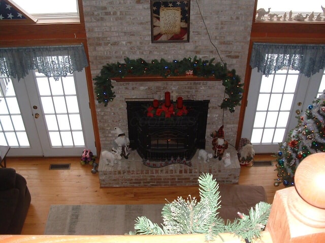 living room with french doors, wood-type flooring, and a brick fireplace