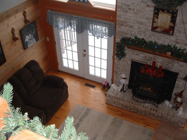 living room featuring hardwood / wood-style flooring, wood walls, and french doors