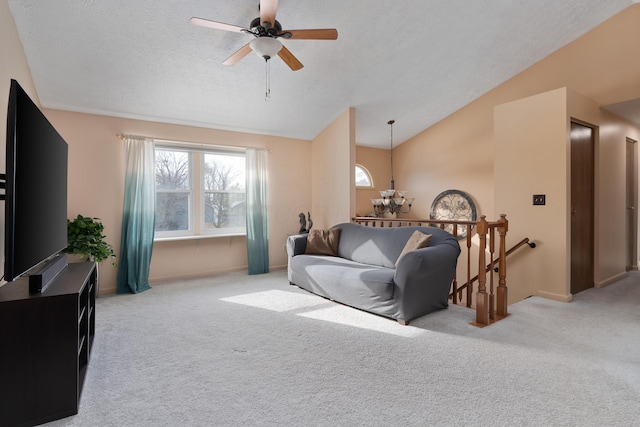 living room featuring ceiling fan, vaulted ceiling, light colored carpet, and a textured ceiling