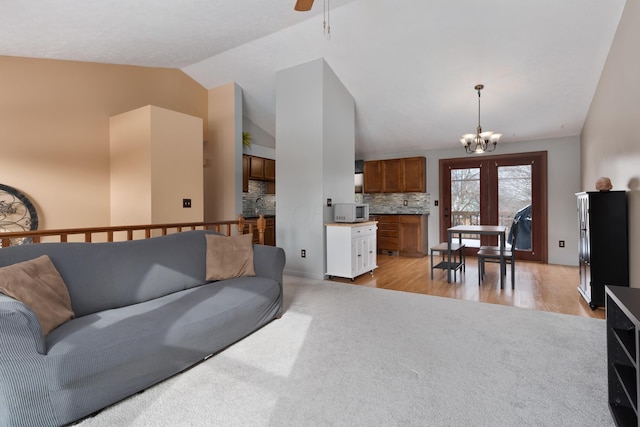 living room with an inviting chandelier, high vaulted ceiling, and light hardwood / wood-style flooring