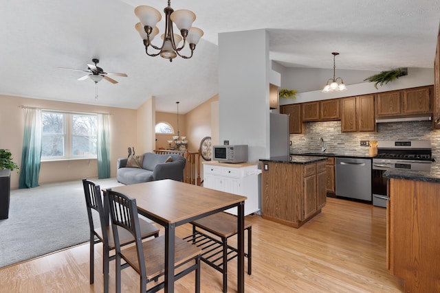 dining area with light hardwood / wood-style flooring, sink, ceiling fan with notable chandelier, and vaulted ceiling