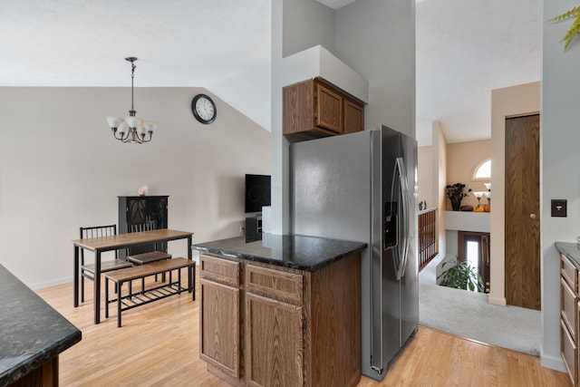 kitchen featuring pendant lighting, high vaulted ceiling, stainless steel fridge, an inviting chandelier, and light hardwood / wood-style flooring