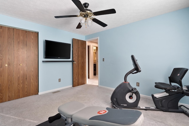 workout room with light carpet, ceiling fan, and a textured ceiling