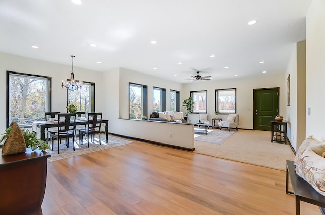 living room with ceiling fan with notable chandelier and light hardwood / wood-style floors