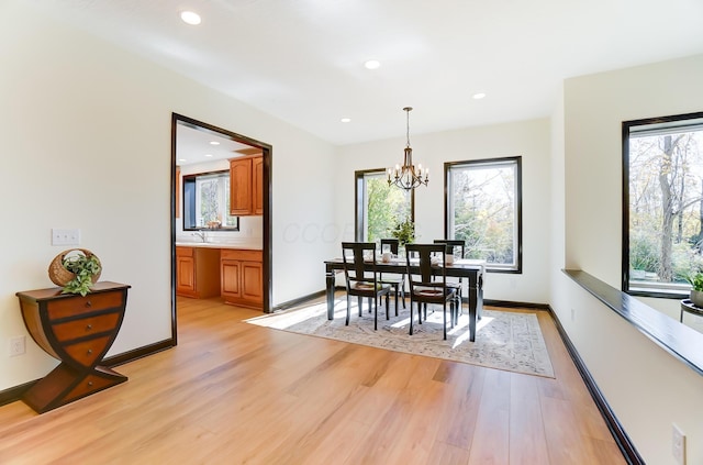 dining space with light hardwood / wood-style flooring, a notable chandelier, and sink