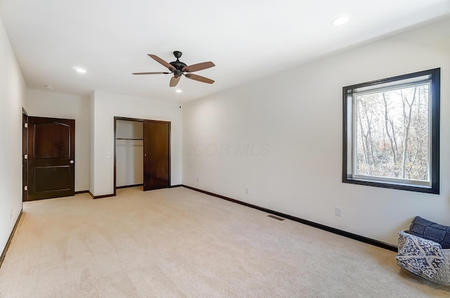 unfurnished bedroom featuring a closet, ceiling fan, and light colored carpet