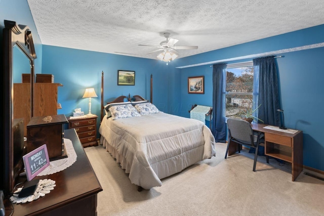 bedroom with ceiling fan, light colored carpet, and a textured ceiling