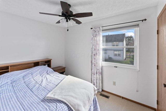 carpeted bedroom featuring ceiling fan and a textured ceiling