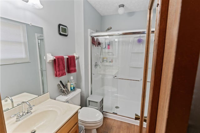 bathroom featuring hardwood / wood-style floors, an enclosed shower, a textured ceiling, toilet, and vanity