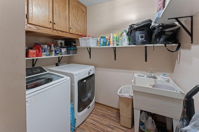 washroom with cabinets, hardwood / wood-style floors, a textured ceiling, and washer and clothes dryer