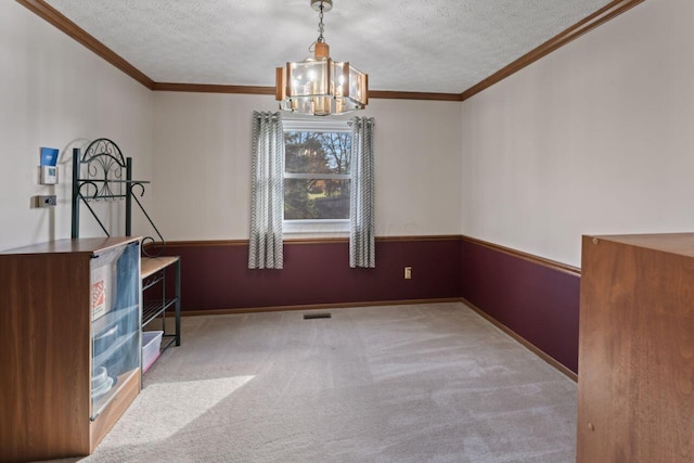 unfurnished dining area with crown molding, light colored carpet, a textured ceiling, and a notable chandelier