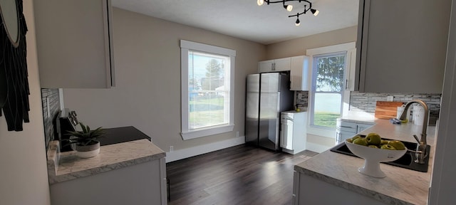 kitchen featuring white cabinets, plenty of natural light, dark hardwood / wood-style flooring, and stainless steel refrigerator