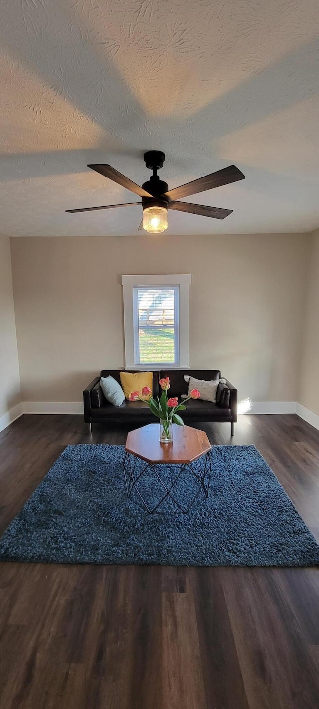 living room featuring a textured ceiling, ceiling fan, and dark wood-type flooring