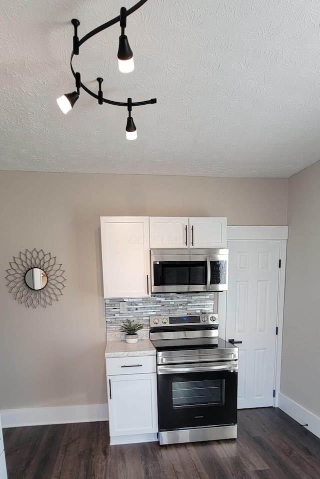 kitchen with a textured ceiling, dark hardwood / wood-style floors, white cabinetry, and stainless steel appliances