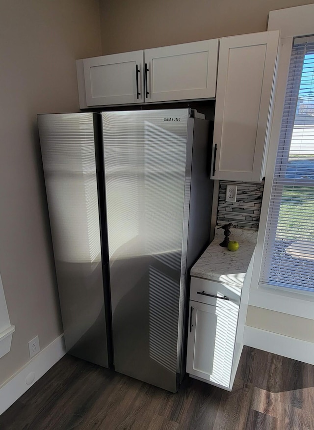 kitchen with light stone countertops, stainless steel fridge, backsplash, dark wood-type flooring, and white cabinets