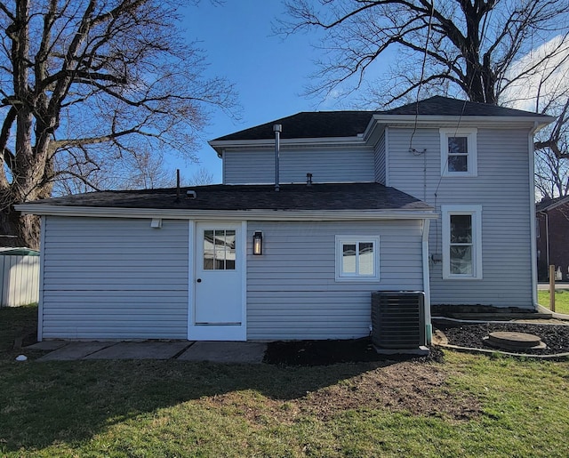 back of house with central air condition unit and a lawn