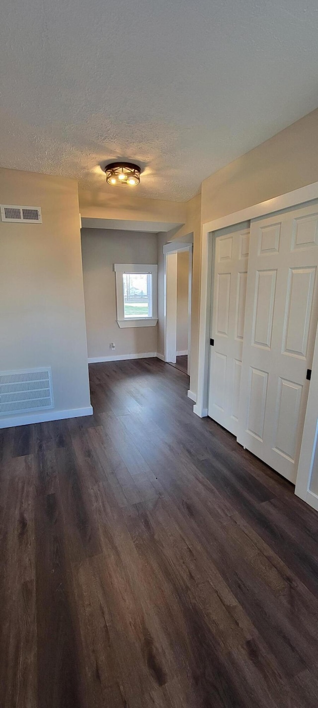 unfurnished room featuring dark hardwood / wood-style flooring and a textured ceiling