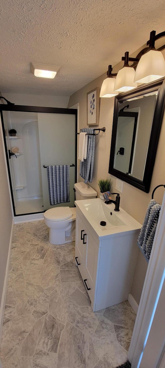 bathroom featuring vanity, a shower with shower door, a textured ceiling, and toilet