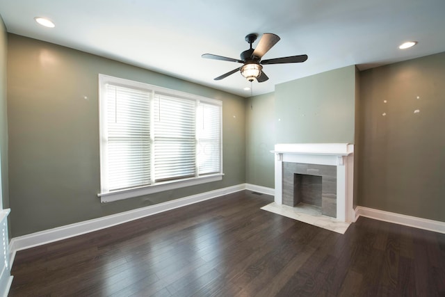 unfurnished living room with ceiling fan, a fireplace, and dark wood-type flooring