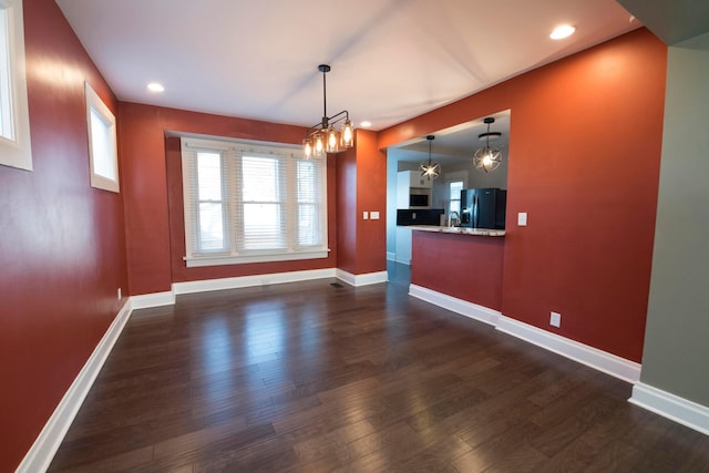 unfurnished dining area with dark hardwood / wood-style flooring and a chandelier