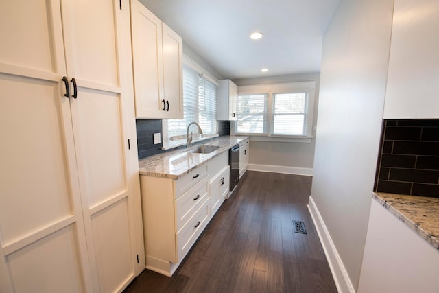 kitchen featuring light stone countertops, white cabinets, and dishwashing machine