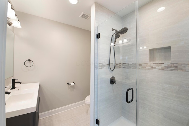 bathroom with tile patterned floors, a shower with door, vanity, and toilet