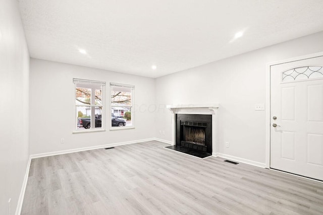 unfurnished living room with light hardwood / wood-style floors and a textured ceiling