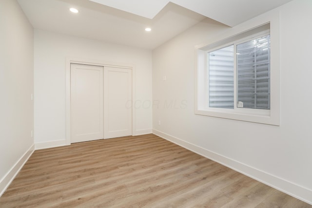 unfurnished bedroom featuring light wood-type flooring, a skylight, and a closet