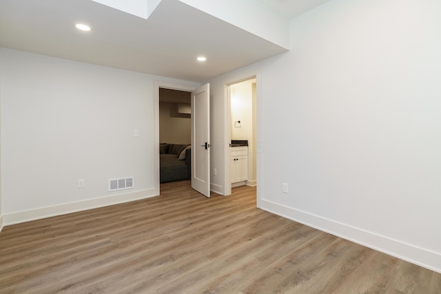 unfurnished room featuring a skylight and light hardwood / wood-style floors