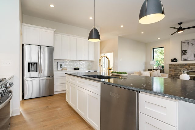 kitchen with sink, stainless steel appliances, white cabinetry, and pendant lighting