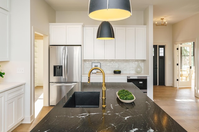 kitchen featuring dark stone countertops, white cabinetry, decorative light fixtures, stainless steel appliances, and decorative backsplash