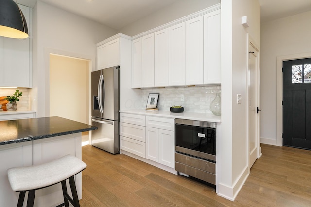 kitchen with light hardwood / wood-style floors, stainless steel fridge with ice dispenser, and white cabinets