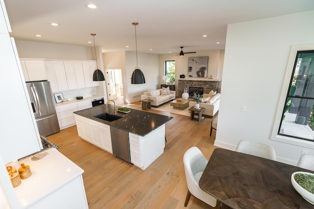 kitchen with sink, a center island with sink, white cabinets, and stainless steel appliances