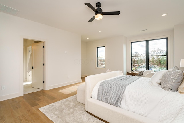 bedroom featuring ensuite bath, light hardwood / wood-style flooring, and ceiling fan