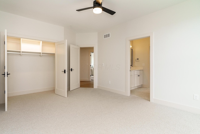 unfurnished bedroom with ceiling fan, a closet, connected bathroom, and light colored carpet