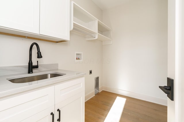 washroom featuring hookup for a washing machine, light hardwood / wood-style floors, hookup for an electric dryer, sink, and cabinets