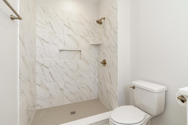 bathroom featuring a tile shower and toilet