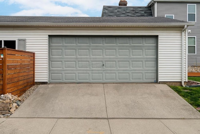 garage featuring driveway and fence