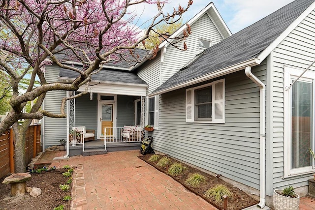 view of exterior entry featuring a porch and fence