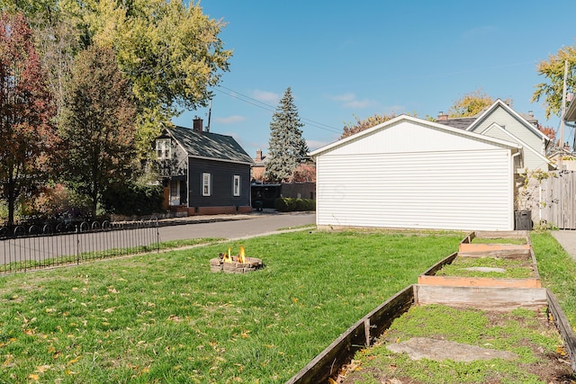 view of yard featuring an outdoor fire pit, a vegetable garden, and fence