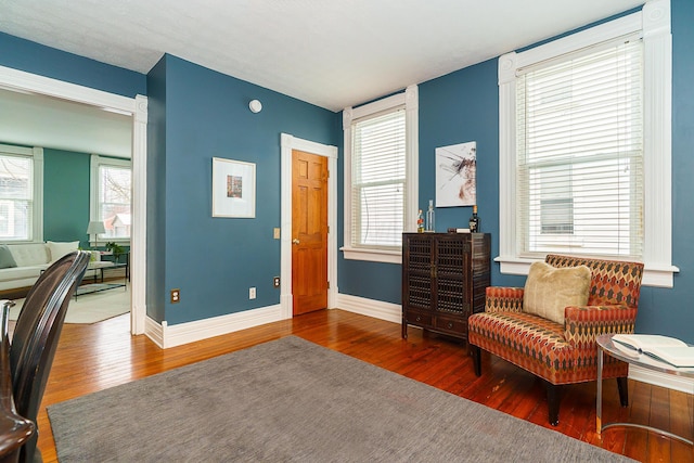 living area with dark wood-type flooring and baseboards