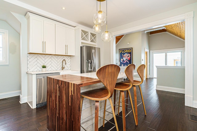 bar featuring lofted ceiling, stainless steel appliances, dark wood-style flooring, decorative backsplash, and decorative light fixtures