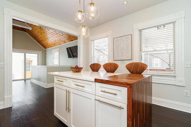 kitchen with lofted ceiling, dark wood-style floors, white cabinets, and decorative light fixtures