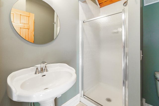 bathroom featuring a stall shower, a sink, and toilet