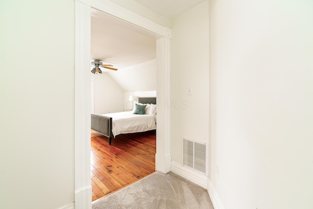 unfurnished bedroom featuring lofted ceiling, ceiling fan, wood finished floors, visible vents, and baseboards