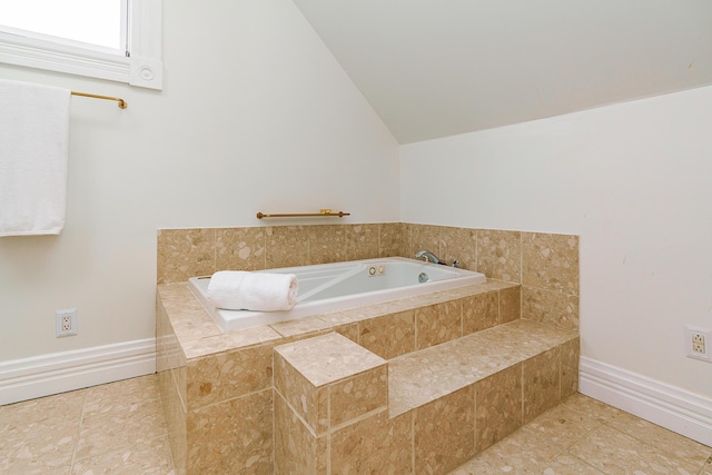 bathroom with tiled bath, lofted ceiling, baseboards, and tile patterned floors