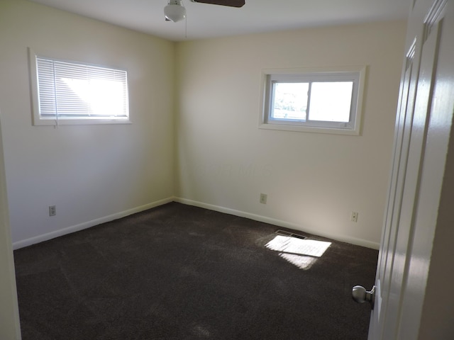 unfurnished room with dark colored carpet, plenty of natural light, and ceiling fan