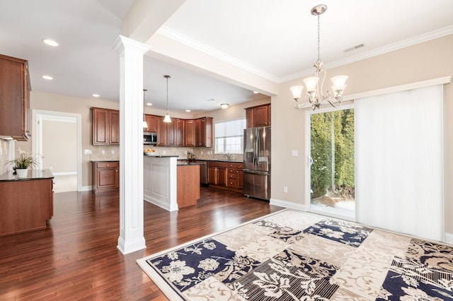 kitchen featuring pendant lighting, appliances with stainless steel finishes, tasteful backsplash, a kitchen island, and ornate columns